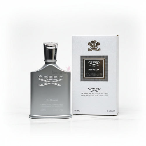 Creed Himalaya perfume bottle and packaging on a textured surface with flowers in the background.